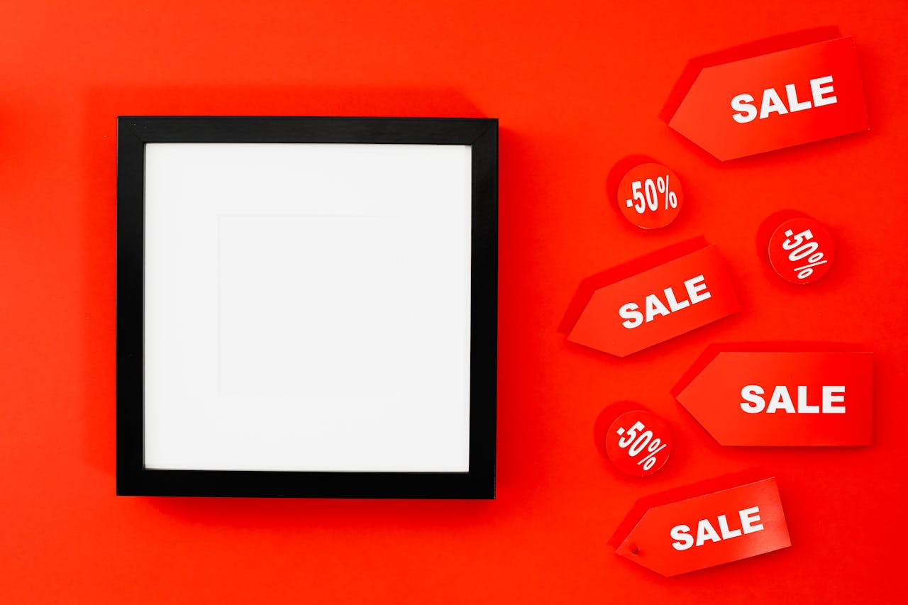 Flat lay of a black frame with sale tags offering 50 percent discount on a red background